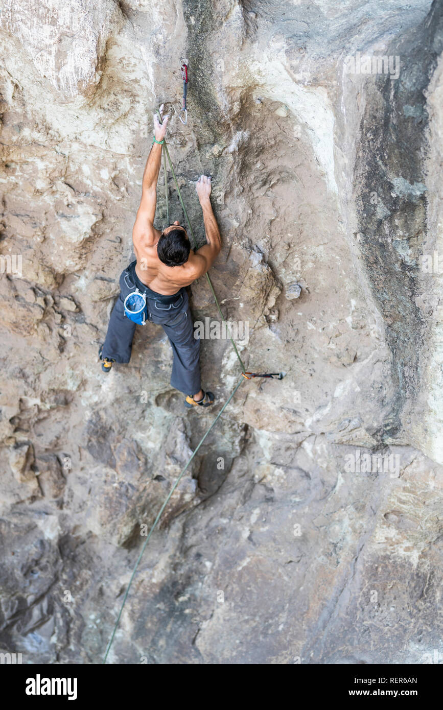 Pratiquer l'escalade sport extrême dans les Andes, au niveau d'une falaise. Un grimpeur mâle fait les mouvements durs avec ténacité et confiance Banque D'Images