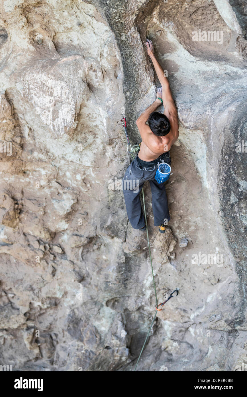 Pratiquer l'escalade sport extrême dans les Andes, au niveau d'une falaise. Un grimpeur mâle fait les mouvements durs avec ténacité et confiance Banque D'Images