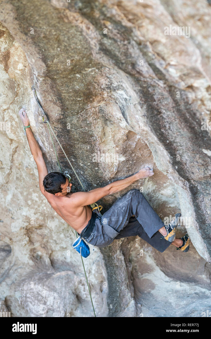 Pratiquer l'escalade sport extrême dans les Andes, au niveau d'une falaise. Un grimpeur mâle fait les mouvements durs avec ténacité et confiance Banque D'Images