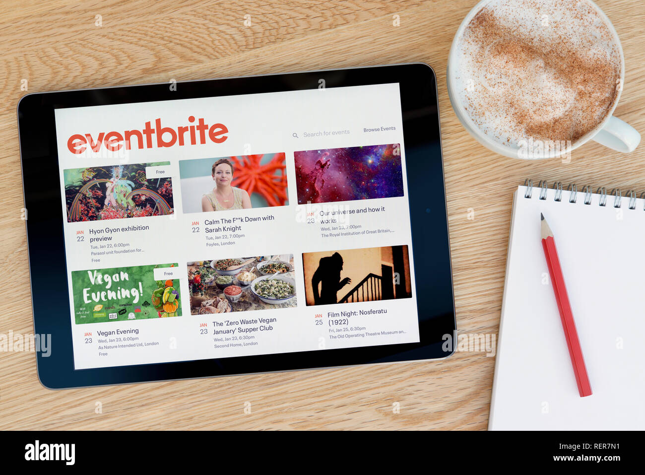 Le site dispose d'Eventbrite de tablette iPad sur un dispositif qui repose sur une table en bois à côté d'un bloc-notes (Editorial uniquement). Banque D'Images