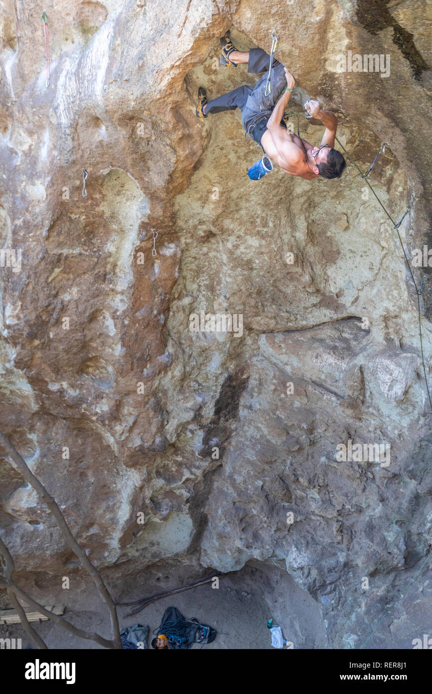 Pratiquer l'escalade sport extrême dans les Andes, au niveau d'une falaise. Un grimpeur mâle fait les mouvements durs avec ténacité et confiance Banque D'Images