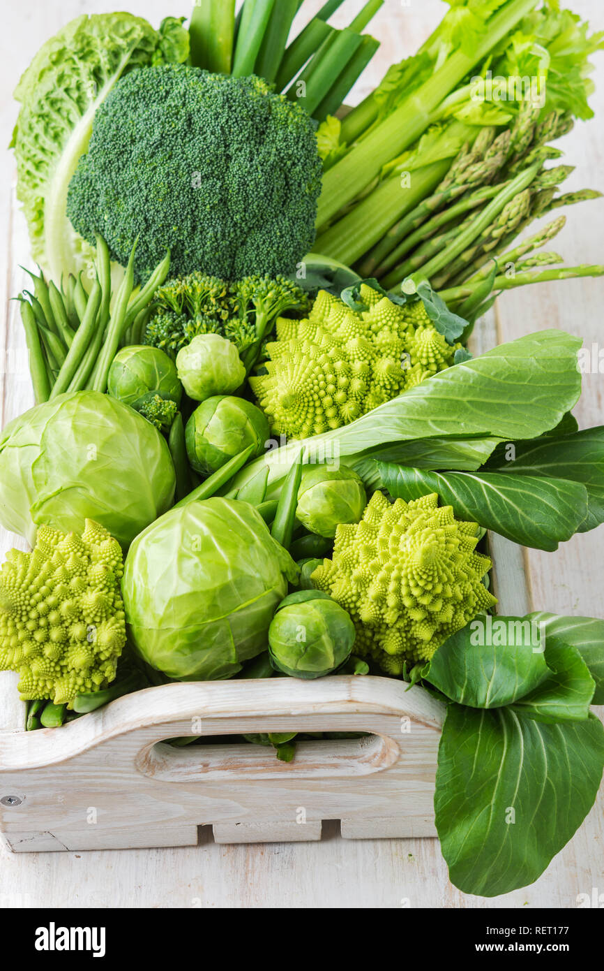 La saine alimentation vegan concept. Les légumes verts sur le tableau blanc les pousses de pois Haricots courgettes avocat céleri bok choy dans boîte en bois, copie, espace Banque D'Images