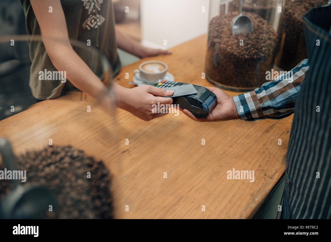 Main de client de payer par carte de crédit sans contact avec la technologie NFC. Garçon avec un lecteur de carte de crédit et la machine avec femelle holding credit card Banque D'Images