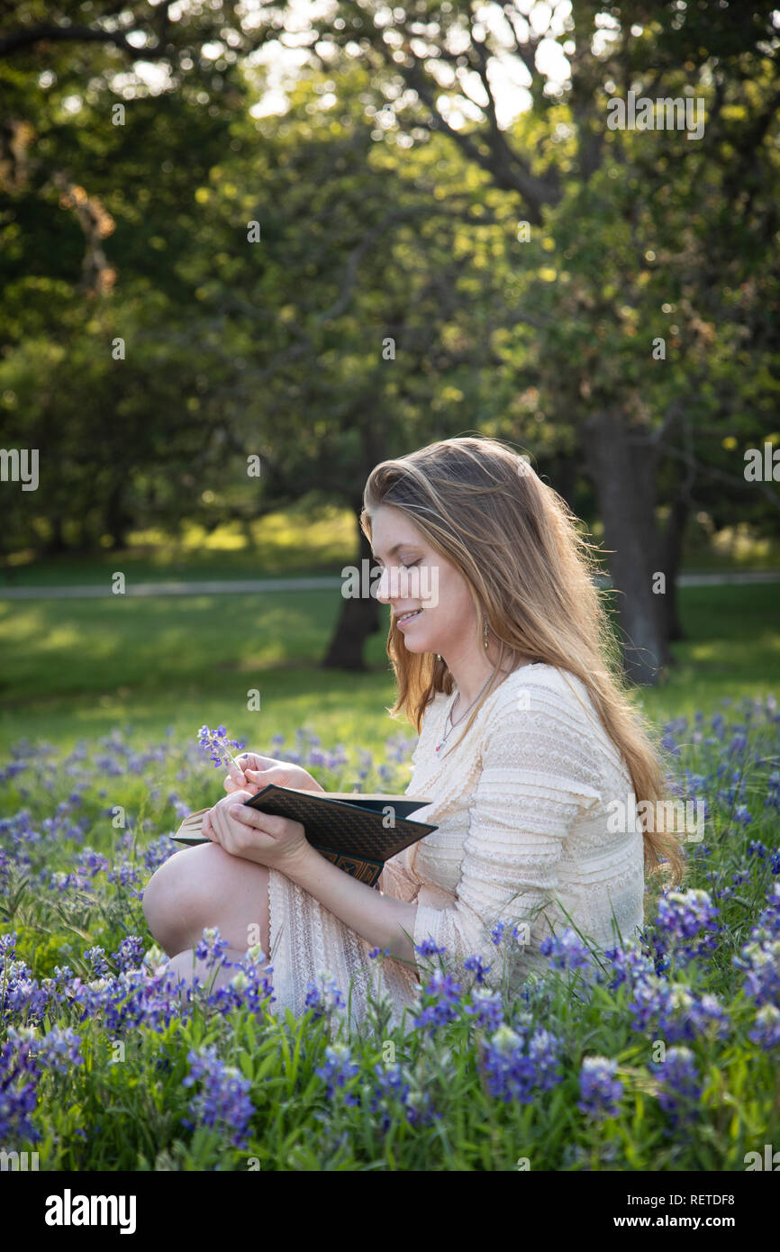 Girl Reading a book in fleurs bluebonnet Banque D'Images