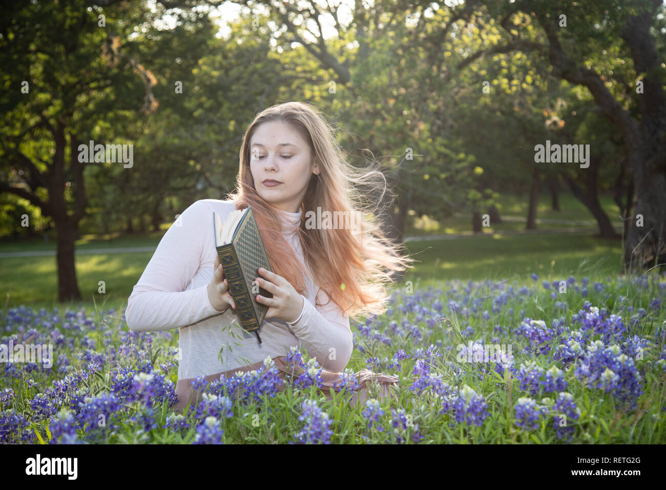Girl Reading a book in fleurs bluebonnet Banque D'Images