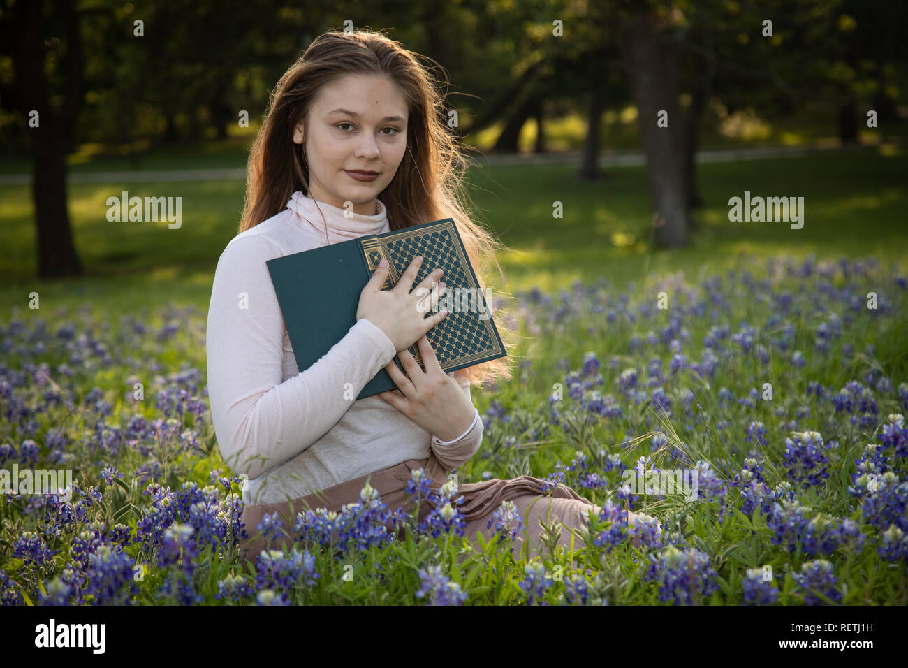 Girl Reading a book in fleurs bluebonnet Banque D'Images