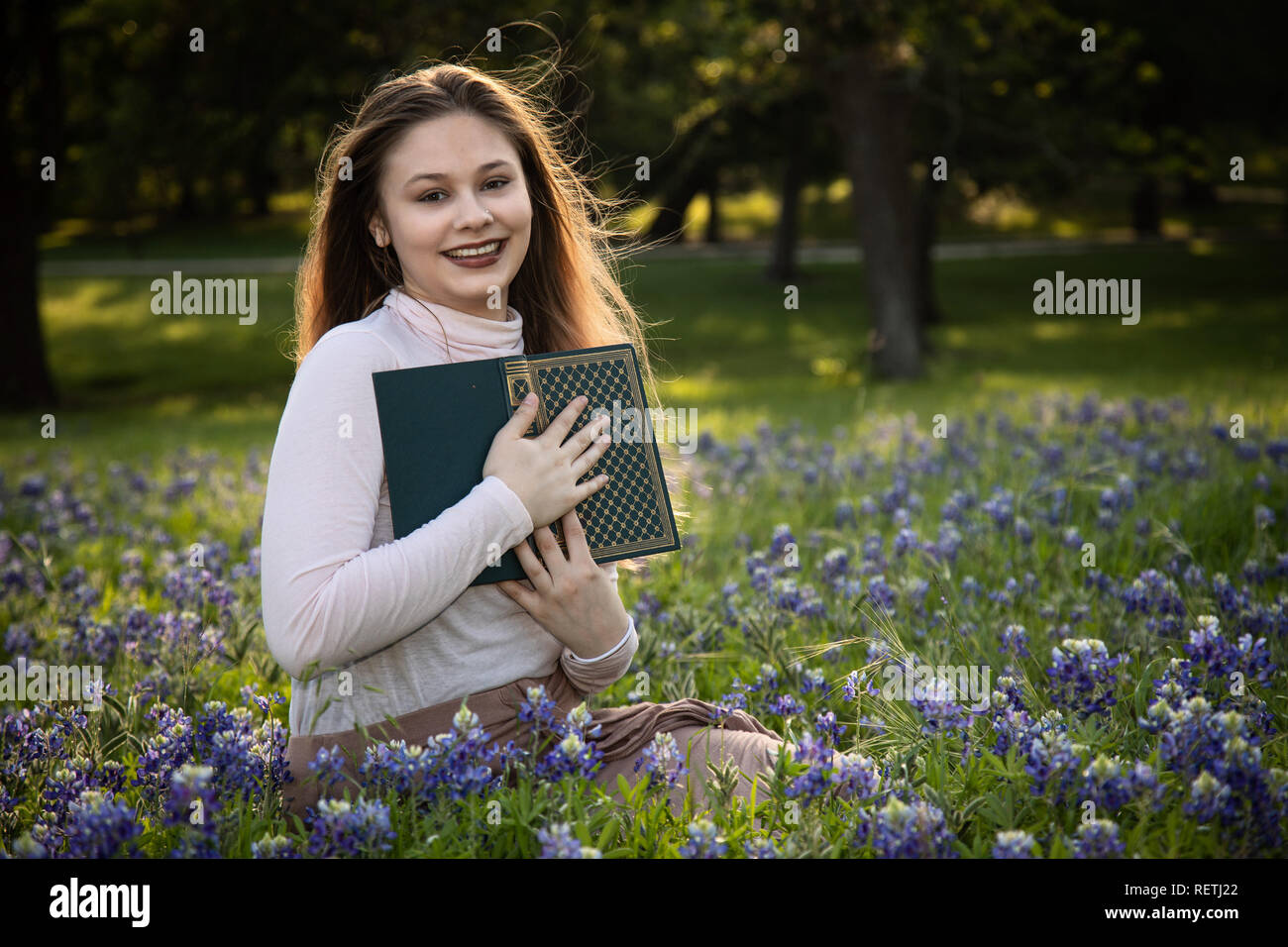 Girl Reading a book in fleurs bluebonnet Banque D'Images