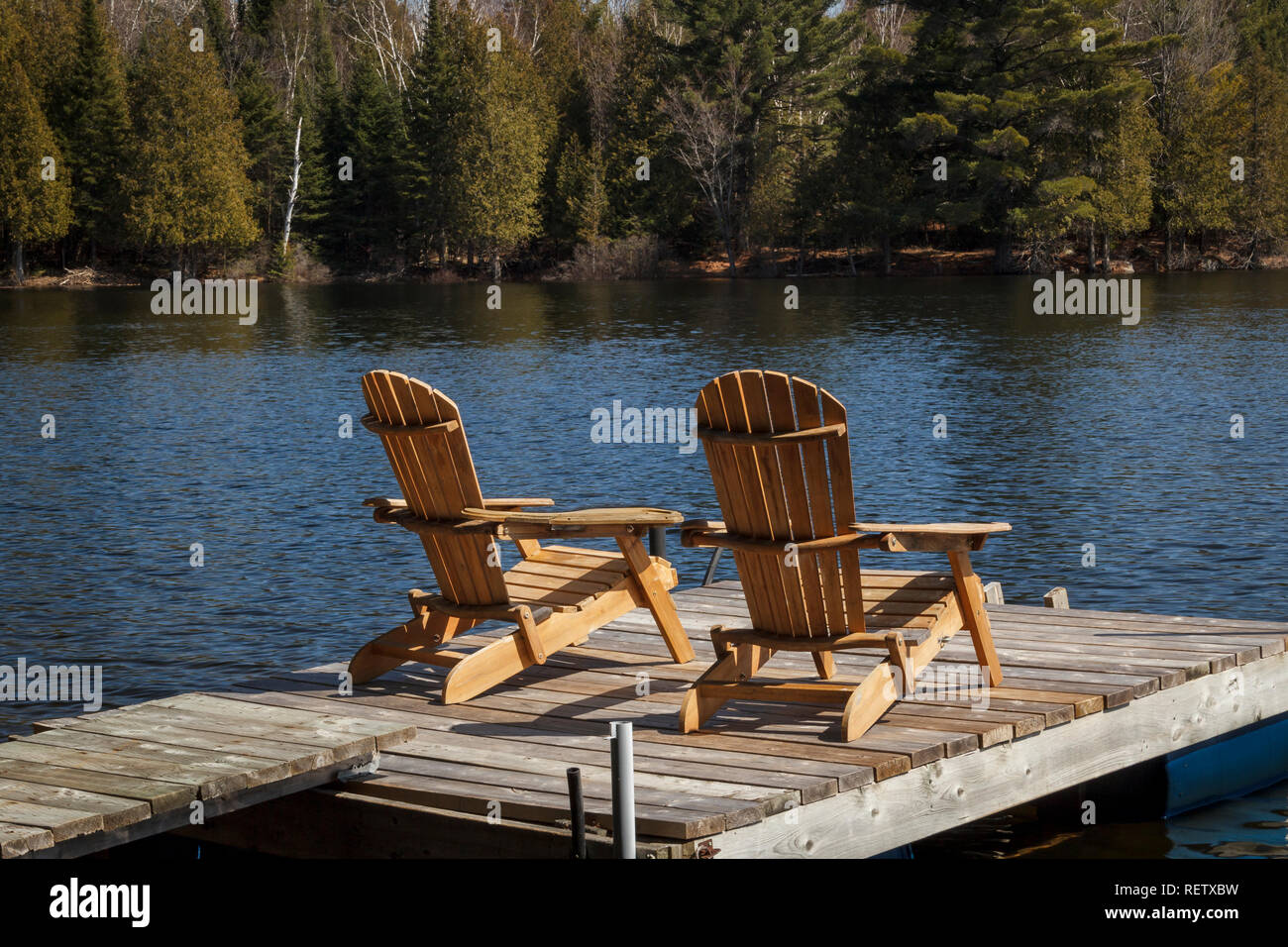 Chaises longues sur un petit quai faisant face au soleil sur une chaude journée d'été sur un lac dans le Nord de l'Ontario, Canada Banque D'Images