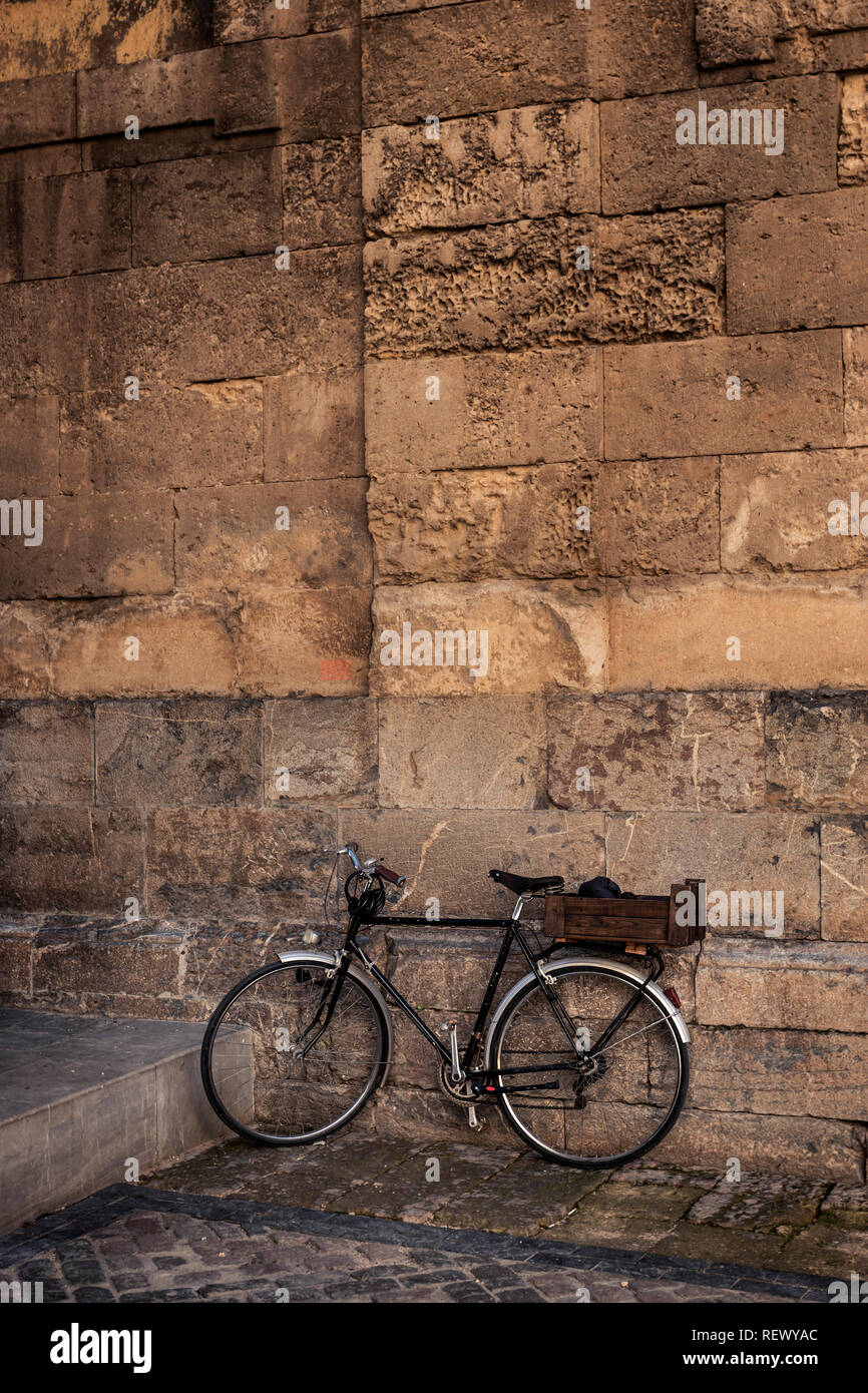 Vélo Vintage noir se pencha sur le vieux mur de pierre avec des taches de rue Banque D'Images