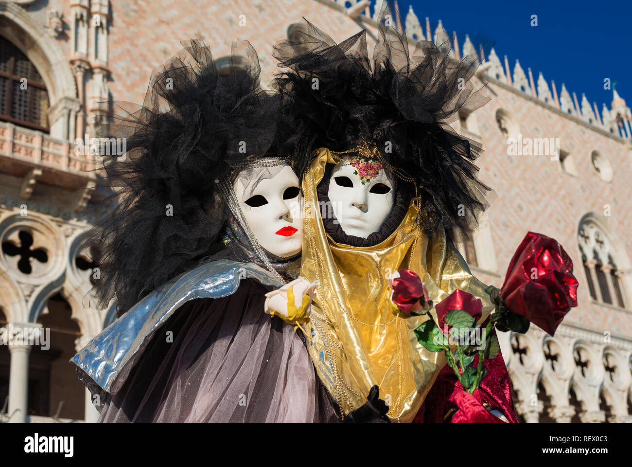 Carnaval de Venise. Deux beaux masques vénitiens avec rose rouge et blanche, en face du Palais des Doges Banque D'Images