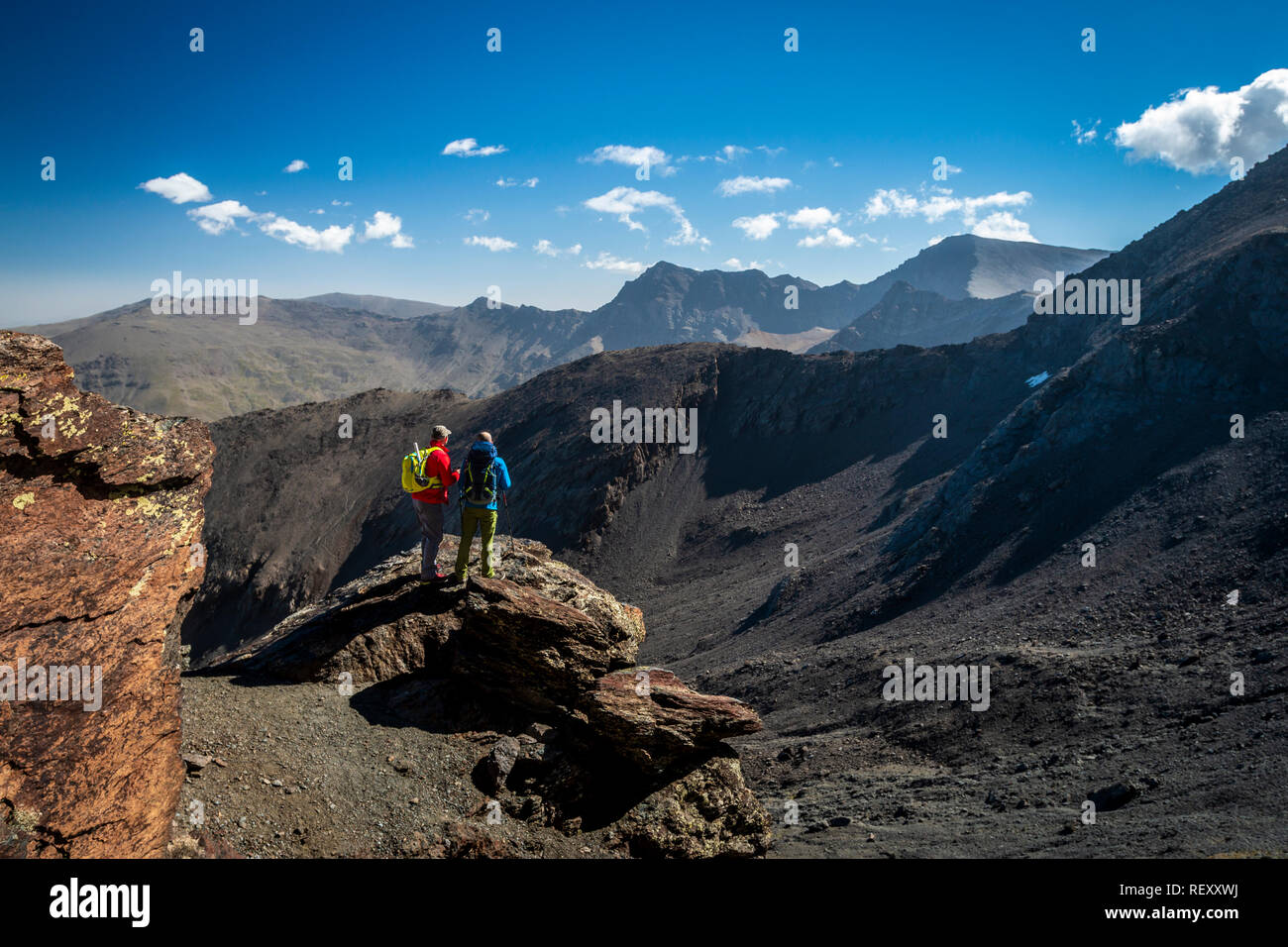 Vue arrière de deux voyageurs masculins debout sur rock et en regardant les montagnes magnifiques sur belle journée ensoleillée en Sierra Nevada, Granada, Espagne Banque D'Images