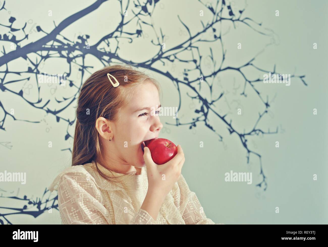 Portrait de profil d'un white Caucasian girl (enfant, kid) manger une pomme rouge. Copier du texte Banque D'Images