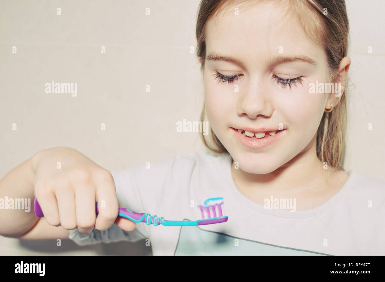 White caucasien enfant (Kid), fille, sourire et se préparer à se laver les dents avec une brosse à dents dans la salle de bains. Vue avant portrait. Copier du texte Banque D'Images
