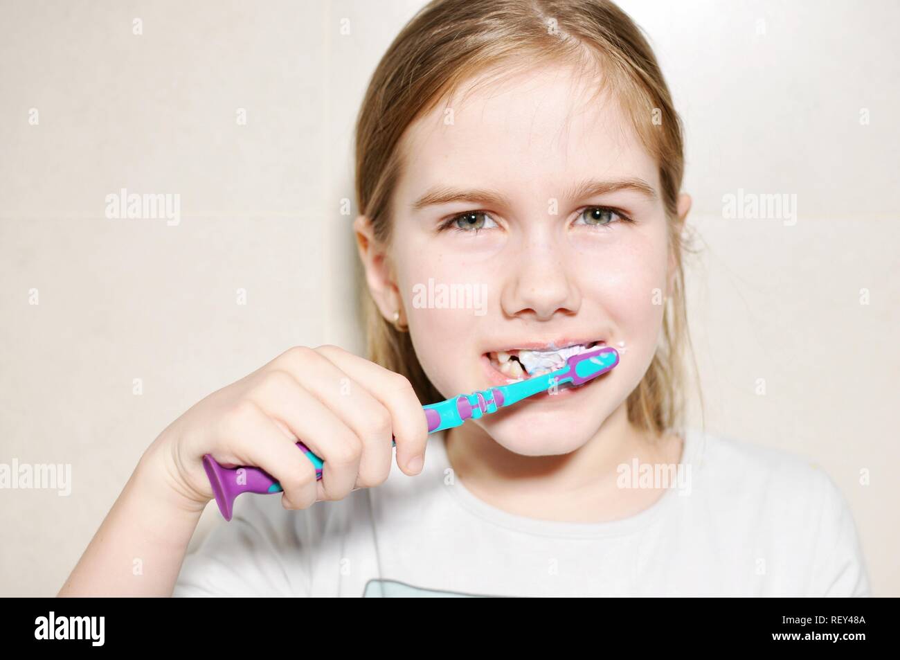 White caucasien enfant (Kid), fille, sourire et de laver ses dents avec une brosse à dents dans la salle de bains. Vue avant portrait. Copier du texte Banque D'Images
