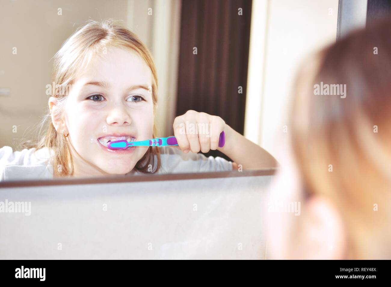 White caucasien enfant (Kid), fille, sourire et de laver ses dents avec une brosse à dents dans la salle de bains. Miroir voir. Les soins dentaires. Banque D'Images