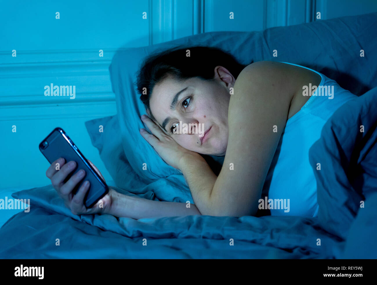 Les jeunes toxicomanes Internet belle femme Chatter et surfer sur internet à l'aide de son téléphone intelligent sleepy ennuyé et assez tard dans la nuit en plus mobiles Banque D'Images