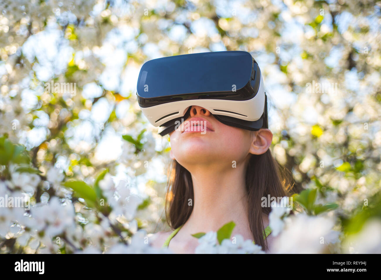 Le jeu est sur. La technologie virtuelle simulation. Cute girl jouer dans  le jardin de printemps. Jeune femme porter des lunettes vr au printemps la  floraison. Jolie fille en casque de réalité
