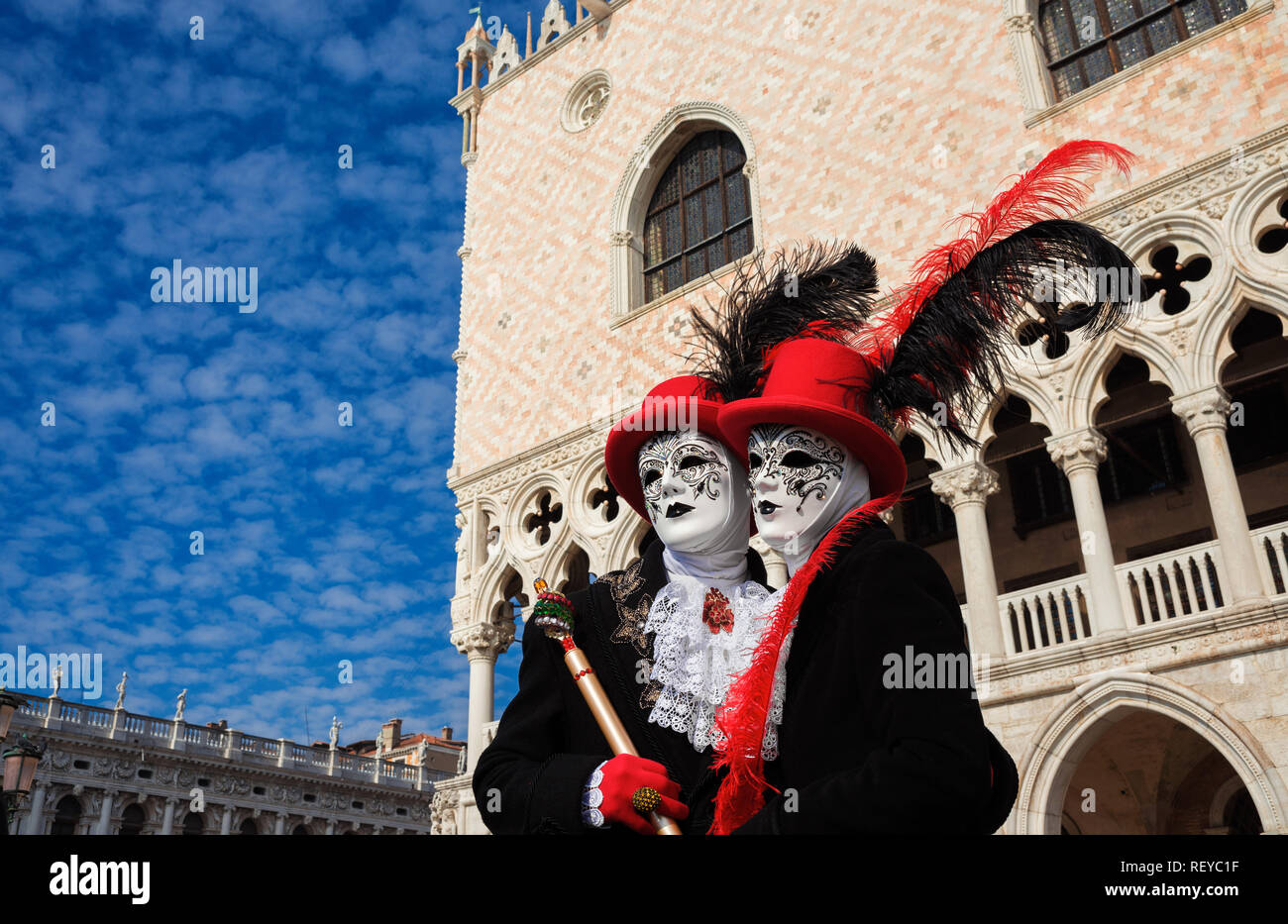 Carnaval de Venise. Deux masques de carnaval vénitien avec le célèbre Palais des Doges et nuages dans l'arrière-plan Banque D'Images