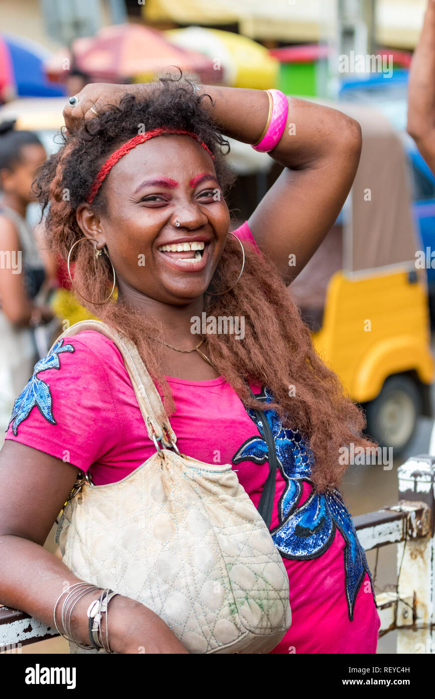 Nosy Be, Madagascar - Janvier 17th, 2019 : une femme malgache locale avec tenue colorée de rire, se penchant sur la rambarde au commer Banque D'Images
