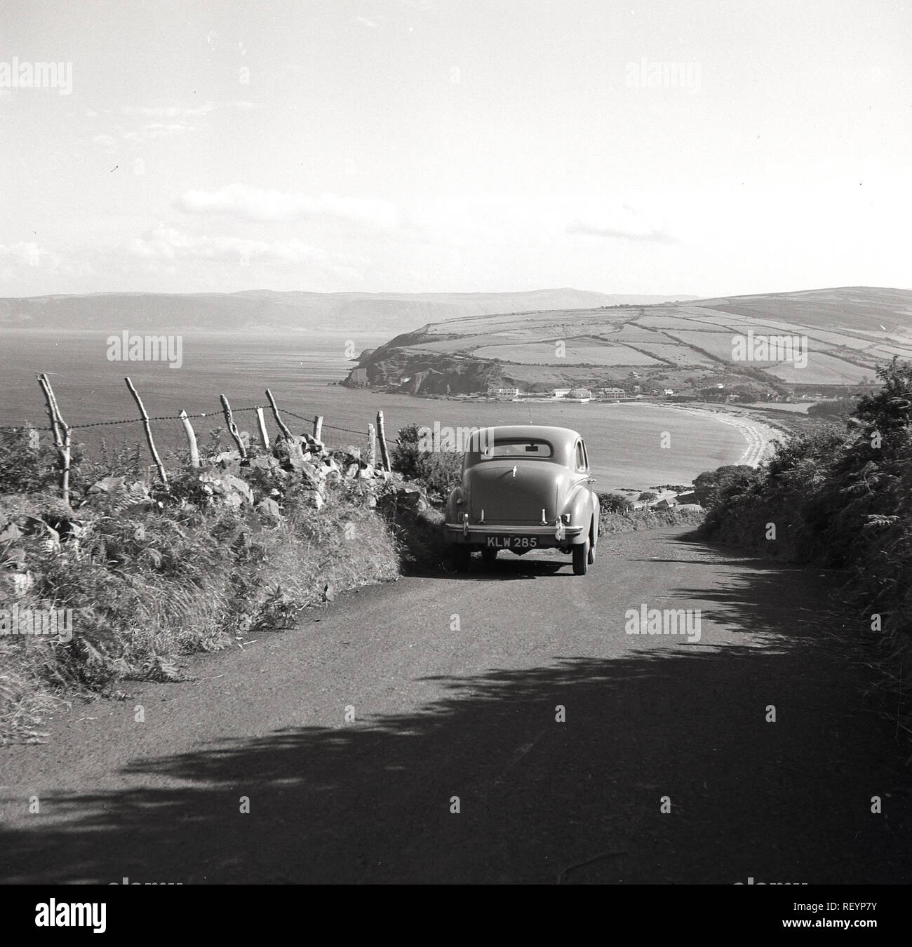 Années 1950, historiques, une voiture Austin de l'époque mis en garde sur la colline sur un chemin de campagne en Co. Antrim donnant sur l'océan Atlantique en Irlande du Nord. Antrim est célèbre pour son magnifique route côtière, la route côtière de la chaussée Banque D'Images