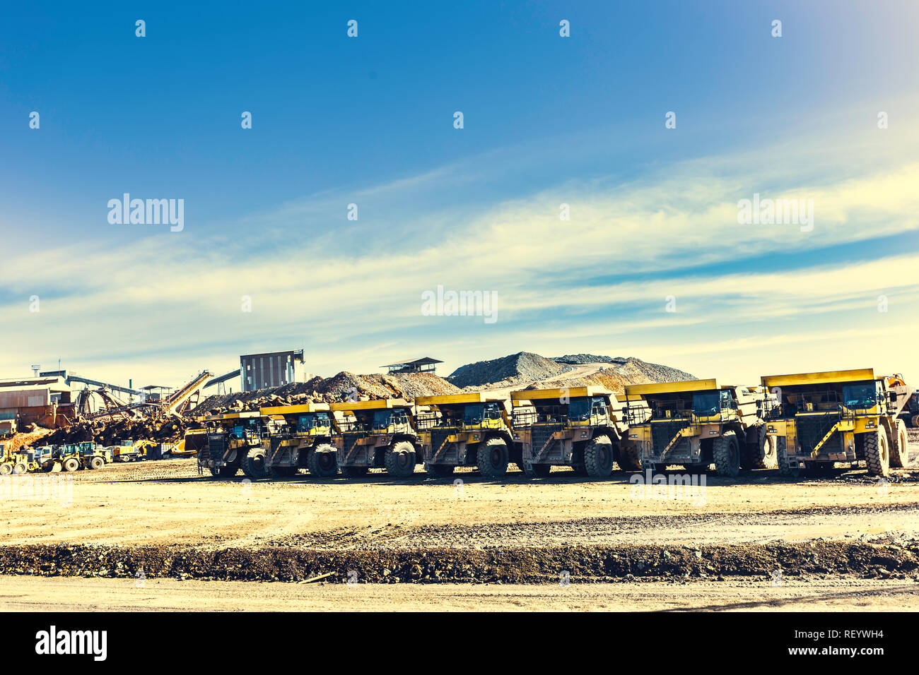 Les grands camions à benne jaune sont mis en ligne dans la mine avec l'ancien mining construction avec le ciel bleu avec des nuages en arrière-plan Banque D'Images