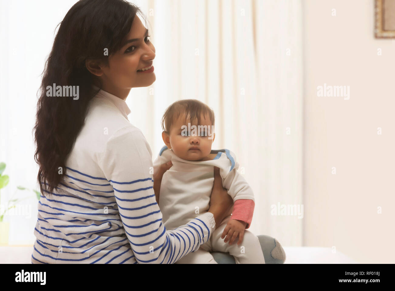 Mère portant bébé à la maison Banque D'Images