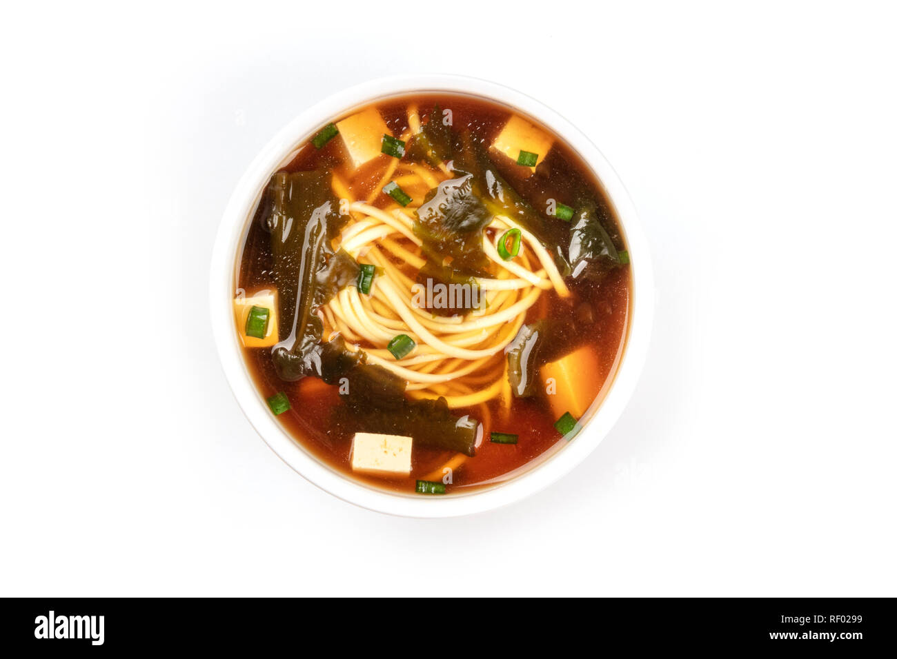 Une photo d'un bol de soupe miso shiru avec le tofu, les oignons verts, les nouilles, et d'algues wakame, tourné par le haut sur un fond blanc avec copie espace Banque D'Images