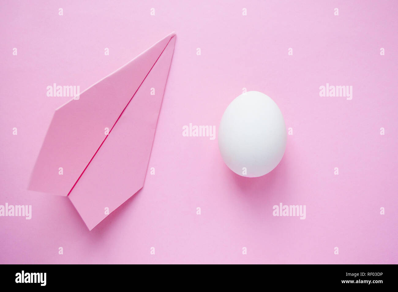 Un seul œuf blanc sur fond rose avec paper plane et copyspace. Concept de voyage. Banque D'Images