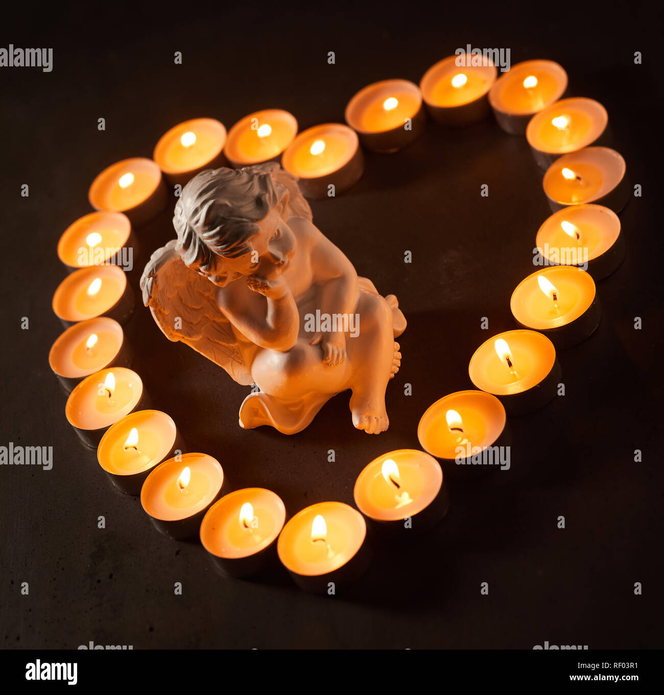 Petit Ange dans un cadre en forme de coeur brûler des bougies sur un fond  sombre de conceptuelle la perte d'un être cher, le chagrin et le souvenir  Photo Stock - Alamy