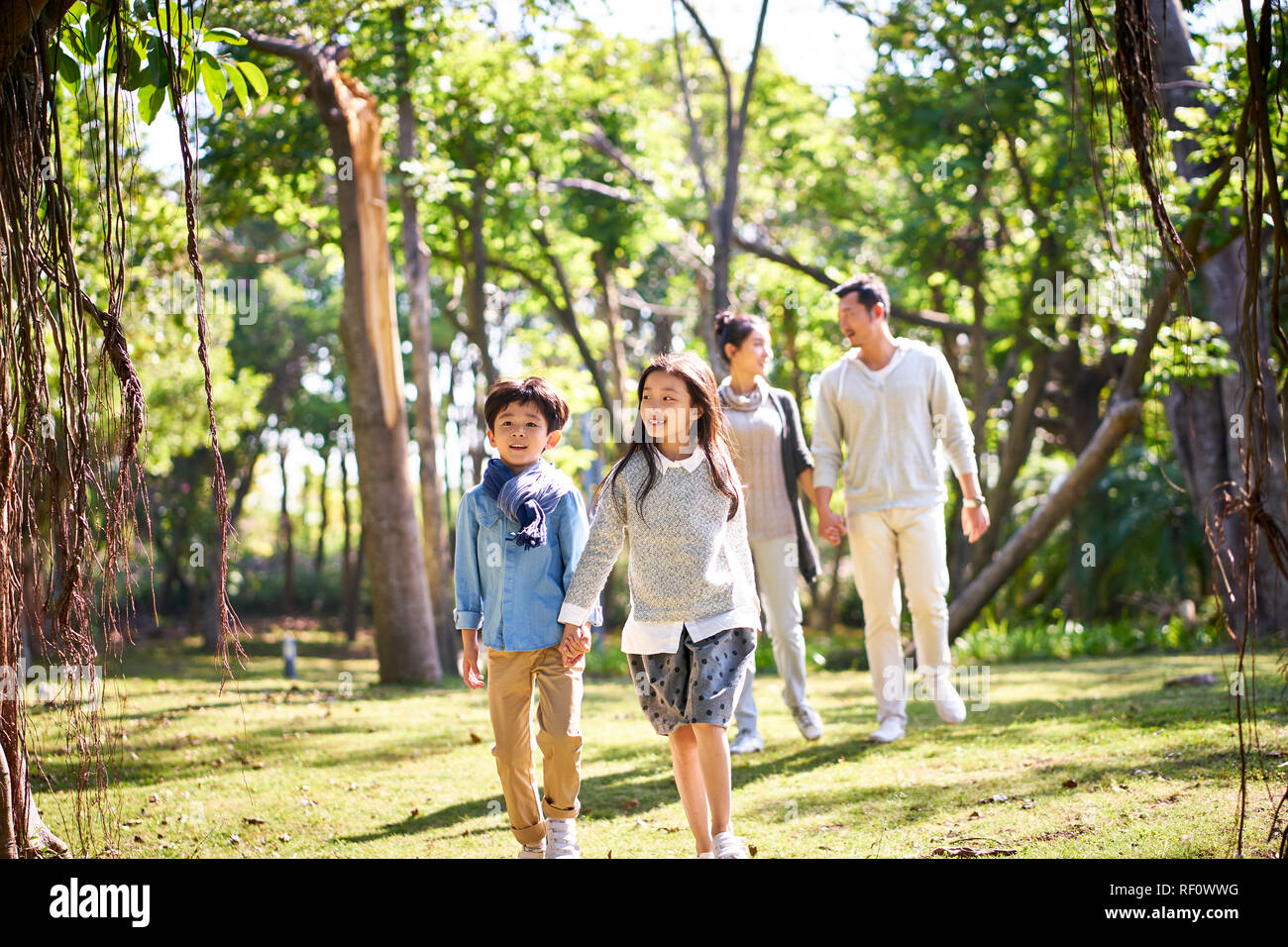 Famille avec deux enfants asiatiques relaxant de marche s'amusant dans le parc heureux et souriants. Banque D'Images
