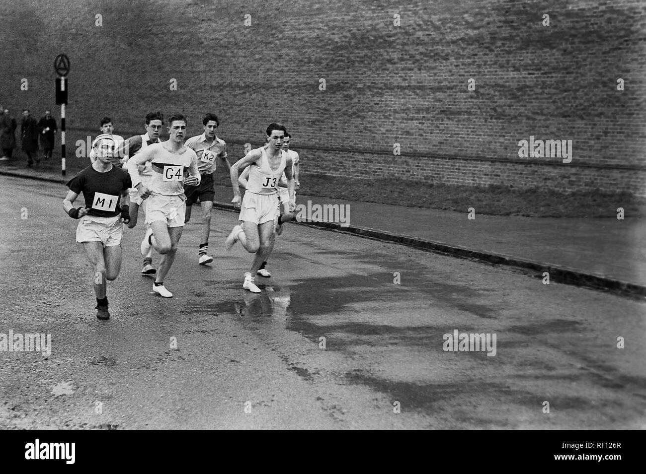 Années 1950, historiques, coureurs homme amateur en compétition dans une course sur route course sur le mouillé rues d'une ville, England, UK Banque D'Images