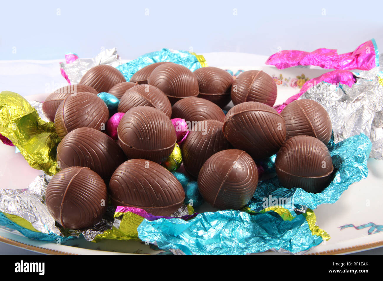 Pile d'oeufs de pâques en chocolat emballé avec le papier aluminium rétractable qui l'entourent sur un fond blanc. Banque D'Images
