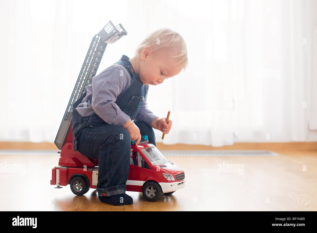 Petit Bebe Garcon Jouant Avec Un Camion De Pompiers Jouet Voiture A La Maison Photo Stock Alamy