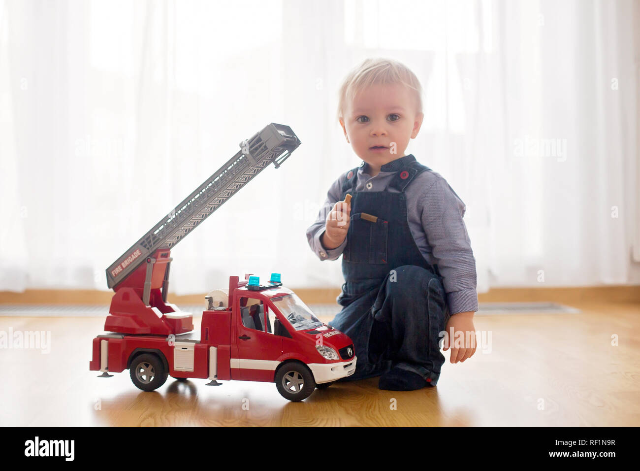 Petit Bebe Garcon Jouant Avec Un Camion De Pompiers Jouet Voiture A La Maison Photo Stock Alamy