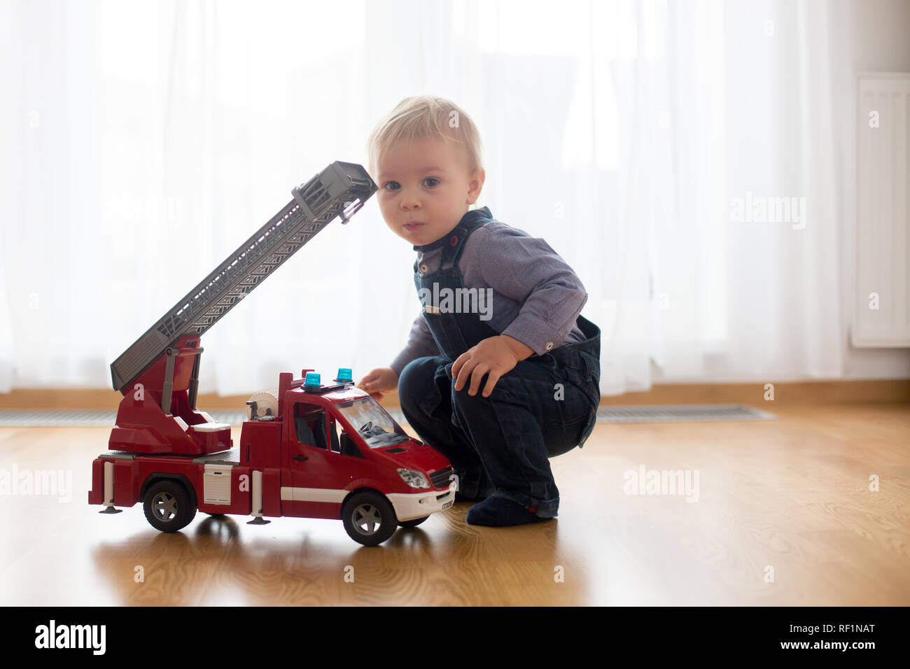 Petit Bebe Garcon Jouant Avec Un Camion De Pompiers Jouet Voiture A La Maison Photo Stock Alamy