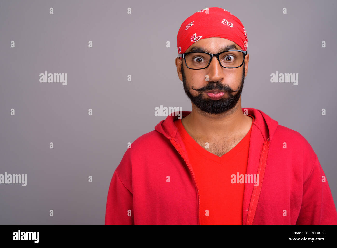 Ennuyer Indian man wearing red shirt et faire drôle de visage Banque D'Images