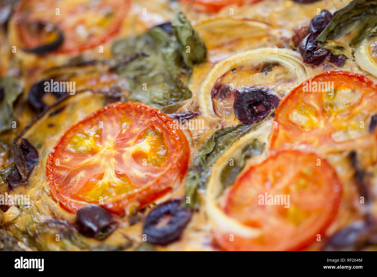 La quiche est un plat d'œufs avec des ingrédients comme les tomates, les épinards, l'oignon et d'olive. Banque D'Images