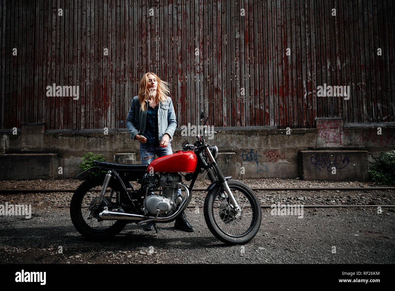 Certain Jeune femme debout à côté de motorcycle Banque D'Images