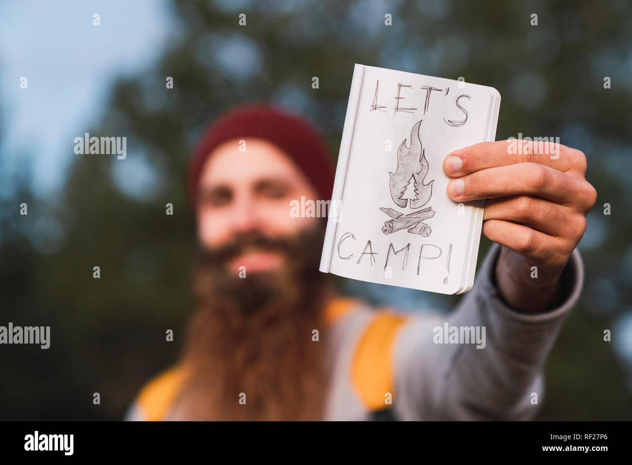 Homme barbu dans une forêt holding "Let's Camp' sign Banque D'Images