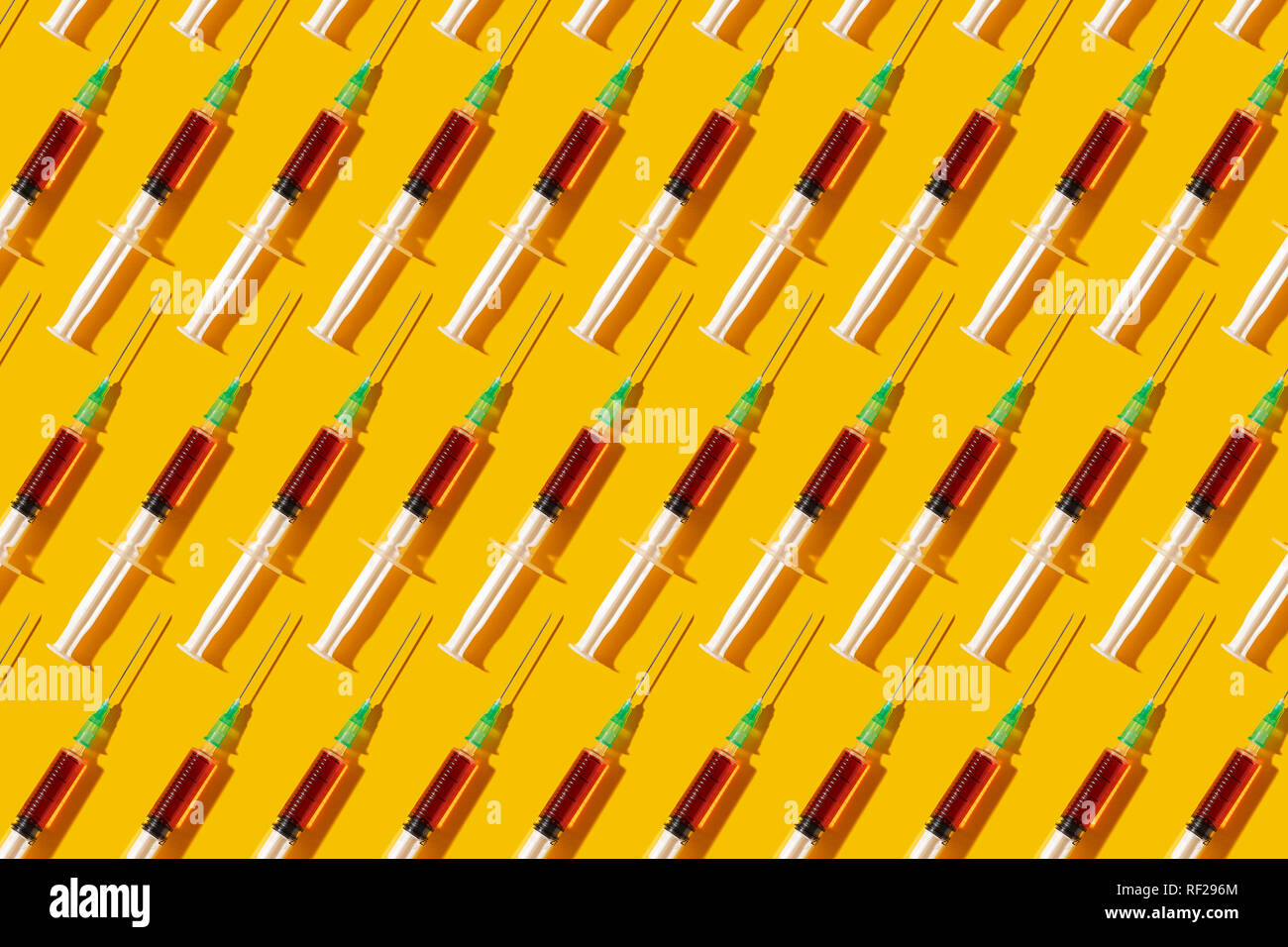 Seringues multiples organisées dans un motif sur fond jaune Banque D'Images