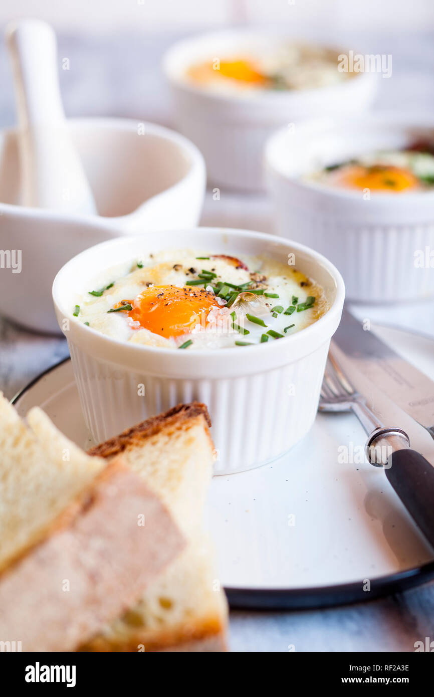 Oefs en cocotte (au four) oeufs individuels aux épinards, feta, bacon, oeufs, et des tranches de pain Banque D'Images Oefs en cocotte (au four) oeufs individuels aux épinards, feta, bacon, oeufs, et des tranches de pain Banque D'Images