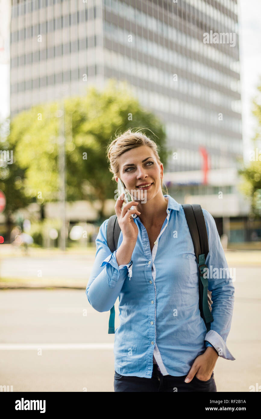 Femme souriante avec sac à dos dans la ville talking on cell phone Banque D'Images