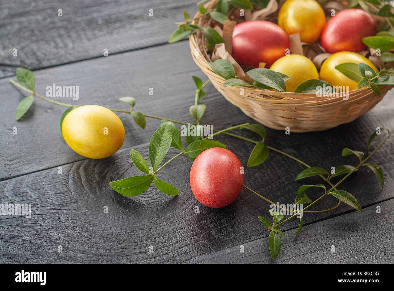 Oeufs de Pâques dans un panier en osier sur un fond de bois. Joyeuses Pâques. Banque D'Images