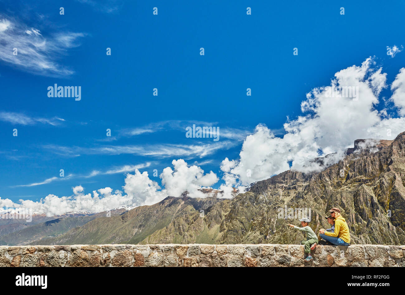 Pérou, Chivay, Canyon de Colca, femme assise avec ses fils sur le mur à la recherche à canyon Banque D'Images