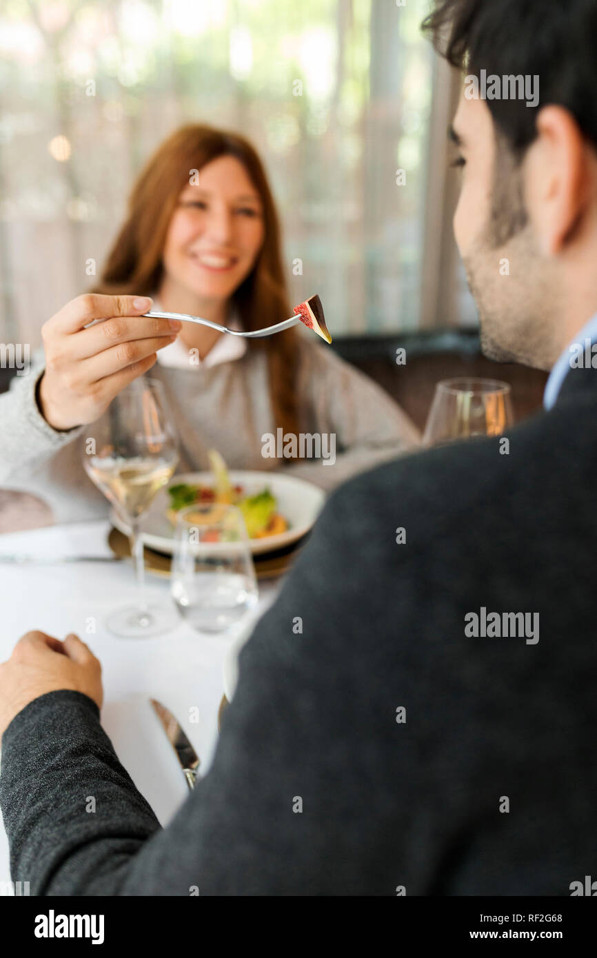 Smiling woman laisser goûter à l'homme la nourriture dans un restaurant. Banque D'Images
