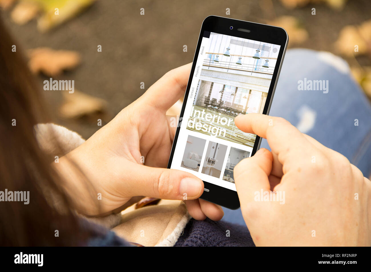 Femme tenant un smartphone 3D généré avec un design intérieur site sur l'écran. Graphiques à l'écran sont constitués. Banque D'Images