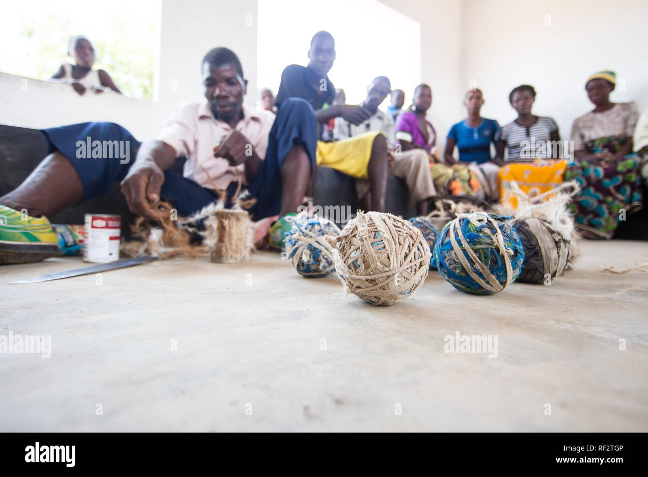 Un homme de l'artisanat des tambours de cacher et chèvre toy balls de brins de tissu dans le cadre d'un programme d'approche communautaire de la Réserve de faune Majete Banque D'Images