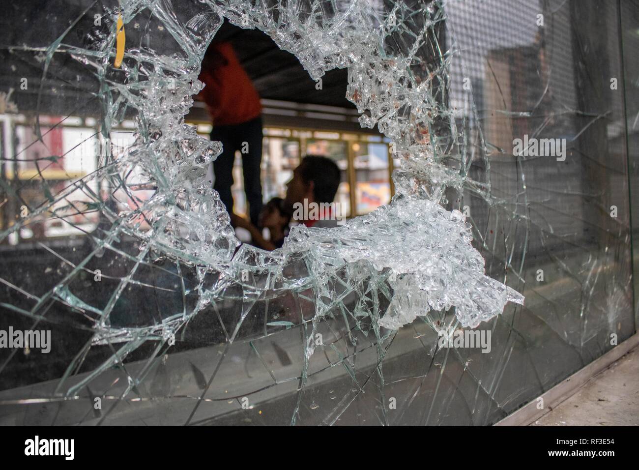 Caracas, Venezuela. 24 Jan, 2019. Un groupe est en train de faire les réparations derrière une vitre cassée. Dans la nuit après l'auto-nomination du chef du parlement comme Guaido chef de l'Etat, les troubles ont éclaté dans la capitale vénézuélienne. Voitures ont été incendiés et des magasins pillés. Les militaires ont mis en garde contre une solution pacifique au conflit. 'Une guerre civile ne va pas résoudre les problèmes du Venezuela", a déclaré le secrétaire de la Défense Padrino. Credit : Rayner Pena/dpa/Alamy Live News Banque D'Images