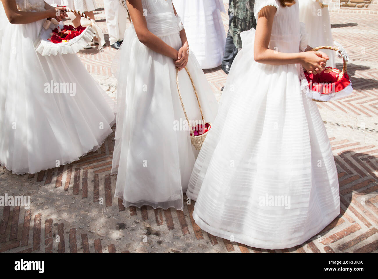Les filles des vêtements blancs et de longues robes communion avec panier de fleurs Banque D'Images