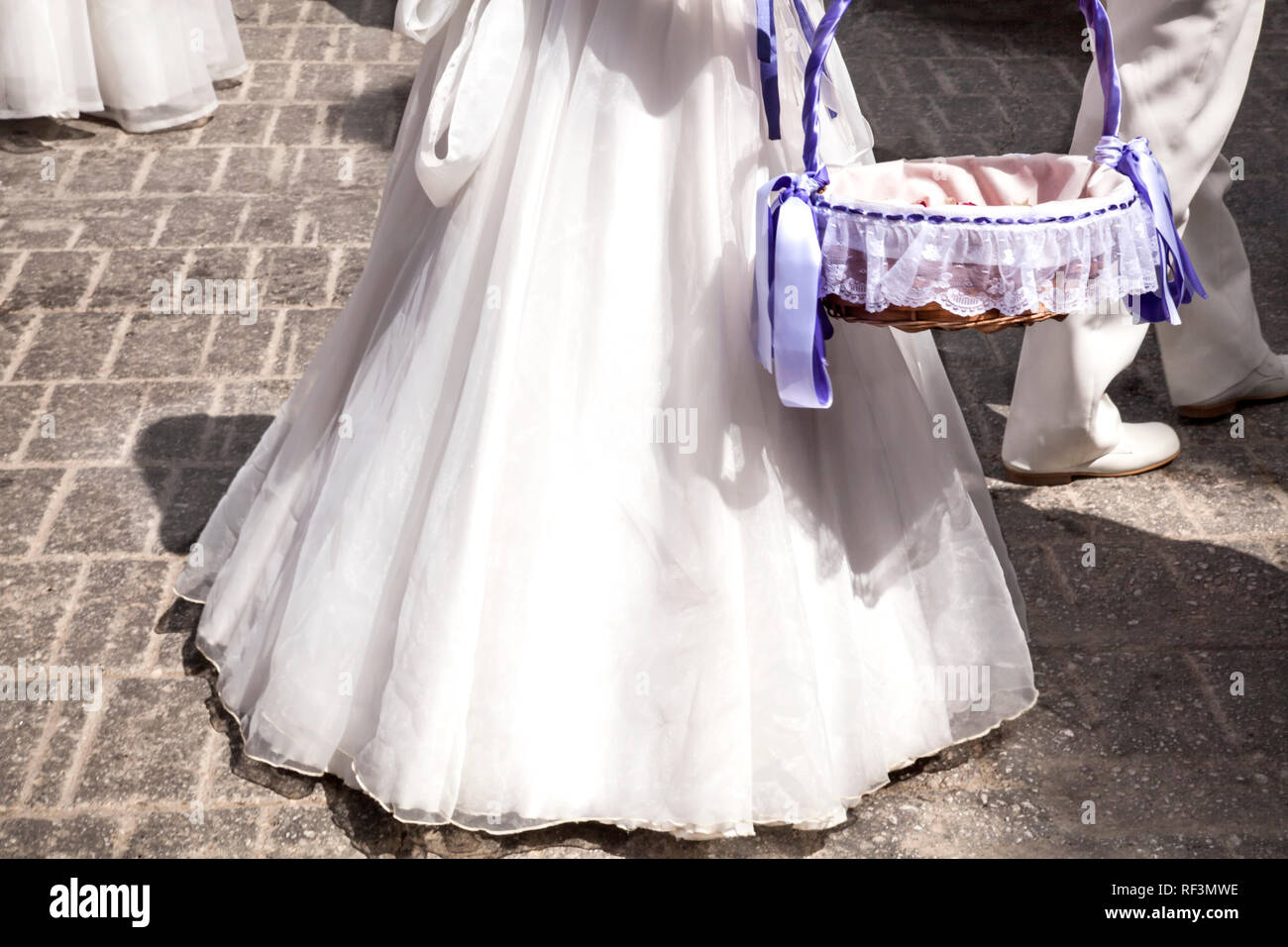 Les filles des vêtements blancs et de longues robes communion avec panier de fleurs Banque D'Images